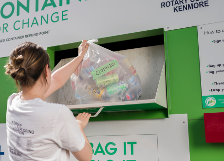 Woman putting clear plastic bag with label into bag drop