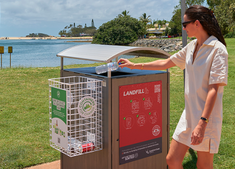 Woman using Container Exchange Point attached to council bin in park area